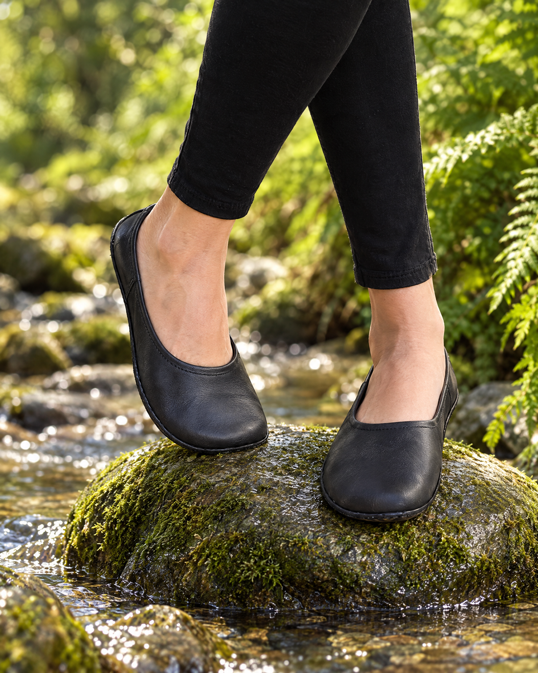 Barefoot ballet flats bending over a mossy stone